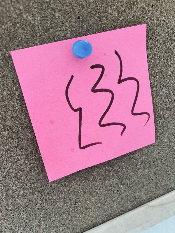 pink post-it with scribbles on a bulletin board